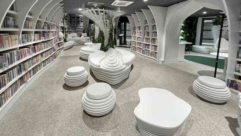 Metroteka w Warszawie – strefa czytelnicza z białymi, warstwowymi siedziskami i regałami w nowoczesnej bibliotece w metrze