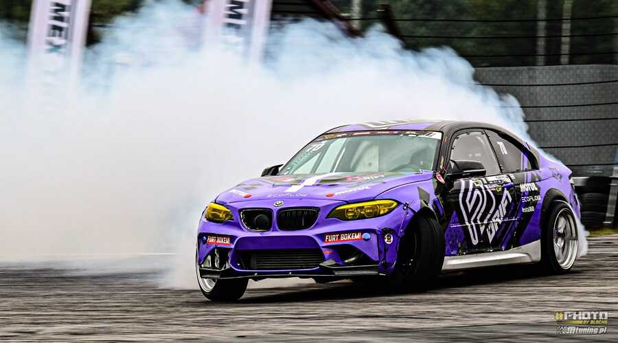 Fioletowe BMW M2 w chmurze dymu podczas driftingu na torze