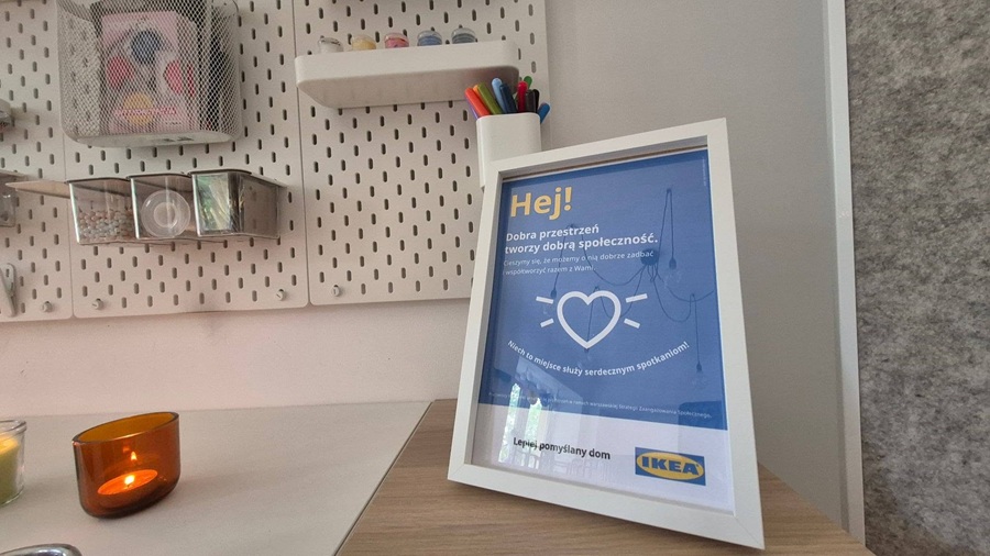 Ramka z napisem „Hej! Dobra przestrzeń tworzy dobrą społeczność" i logo IKEA w Punkcie Wsparcia Psychicznego „Potrzebna" w Warszawie