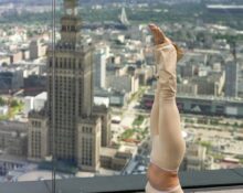 Uczestniczka wykonuje pozycję jogi na tarasie widokowym Varso Tower w Warszawie. W tle widoczny Pałac Kultury i Nauki oraz panorama centrum stolicy.
