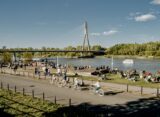 Spacerowicze i rowerzysta na terenach zielonych nad Wisłą