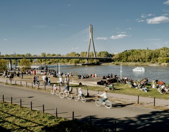 Spacerowicze i rowerzysta na terenach zielonych nad Wisłą